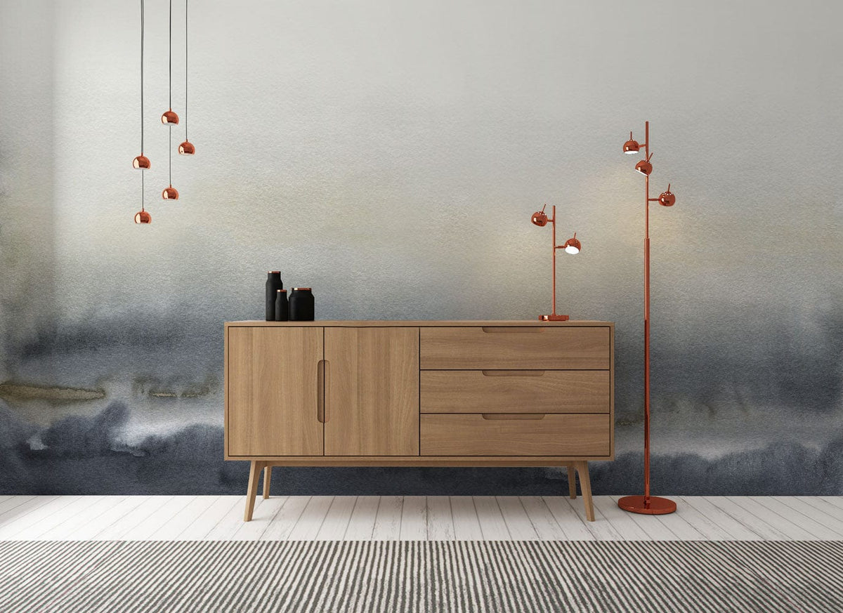 Misty Grey Ombre Watercolour Mural Wallpaper with wood sideboard, red lamps, striped rug, white flooring.