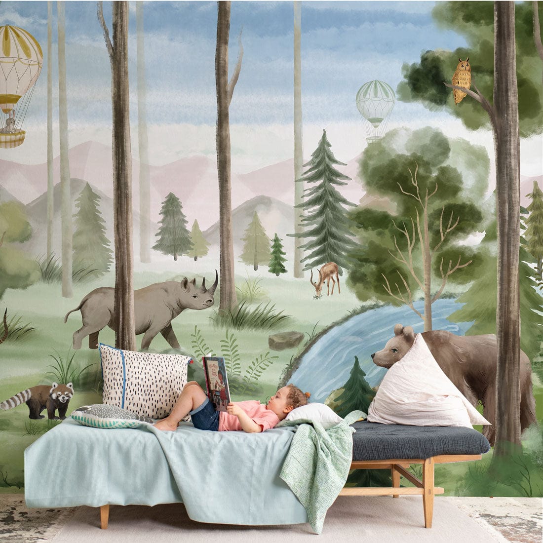 Enchanted Woodland Adventure Mural Wallpaper in pastel safari nursery with blue sofa and rug.