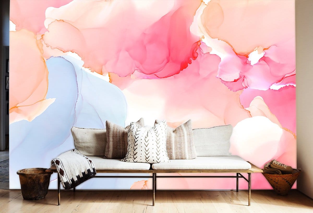 Abstract mural wallpaper in pink and blue tones behind beige sofa, wooden flooring, and woven basket.