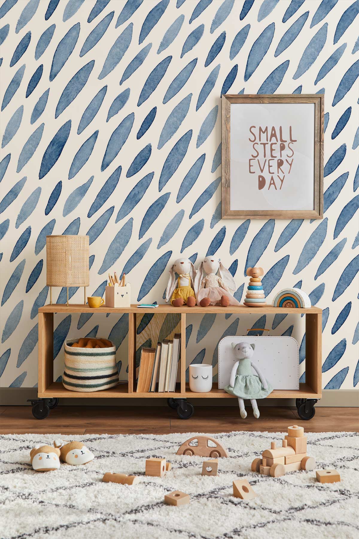 Blue abstract watercolour leaf wallpaper in modern nursery with wooden shelf and framed art.