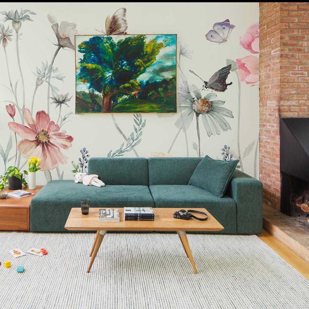 Vintage pastel floral butterfly mural wallpaper in living room, green sofa, wooden table, grey rug.