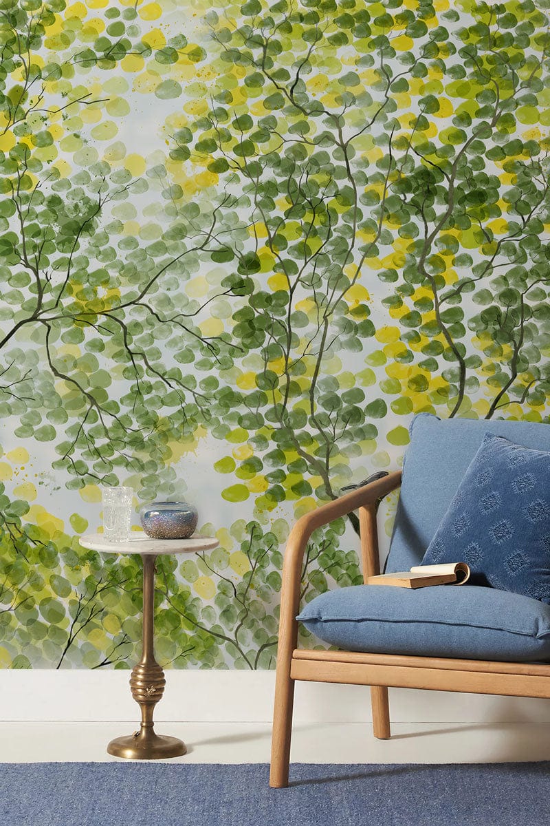 Serene Green Tree Pattern Mural Wallpaper with blue sofa chair, gold side table in a living room.