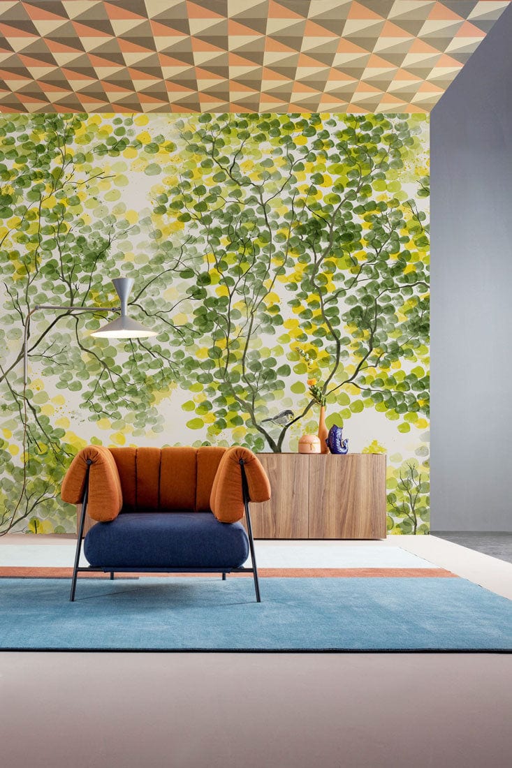 Serene Green Tree Patterned mural in modern living room with orange-blue chair and geometric ceiling.