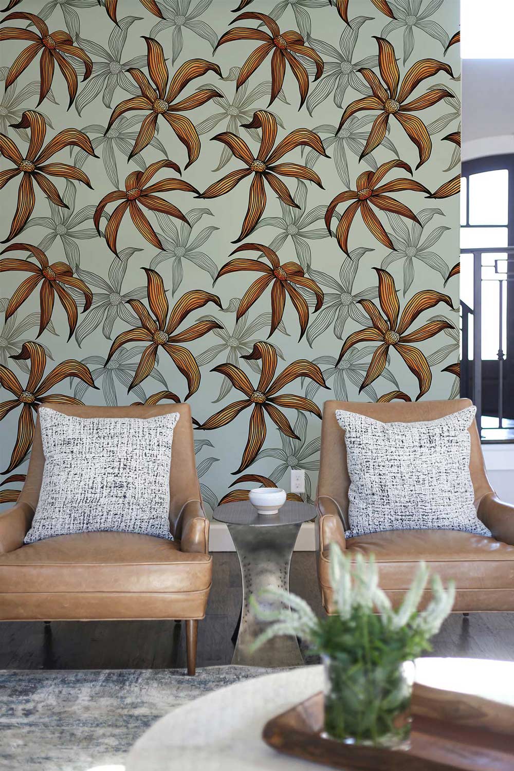 Vintage botanical wallpaper with earthy floral pattern, brown leather armchairs, neutral room setting.