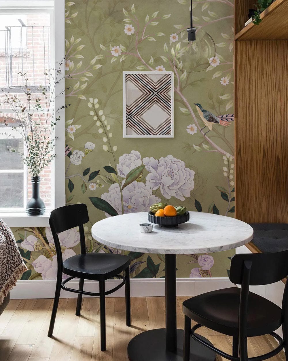 Elegant botanical mural wallpaper in dining room with black chairs, round table, and light wood flooring.