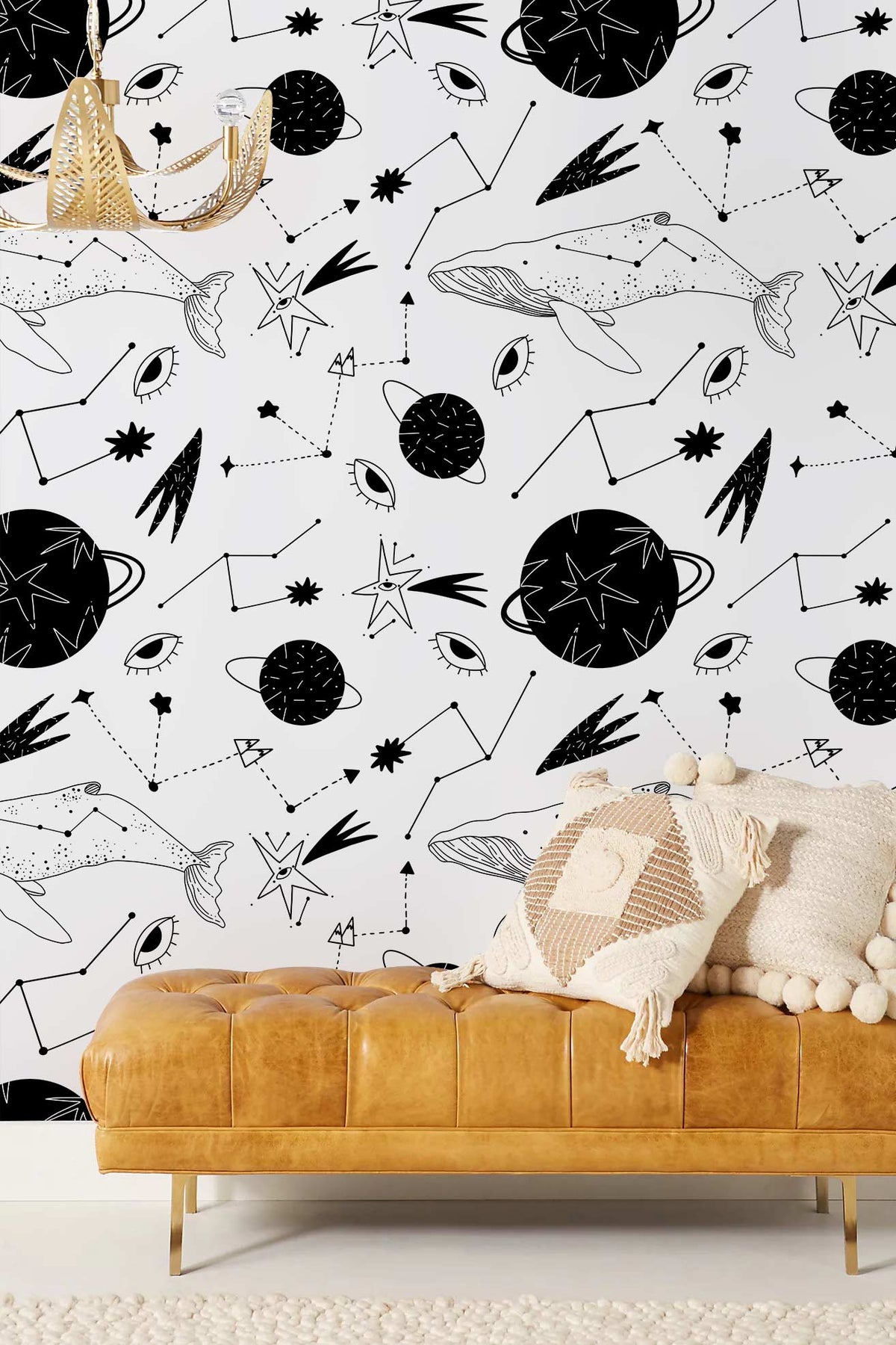 Monochrome Cosmic Whale wallpaper; tan leather sofa; modern chandelier; cosy pillows; living room setting.