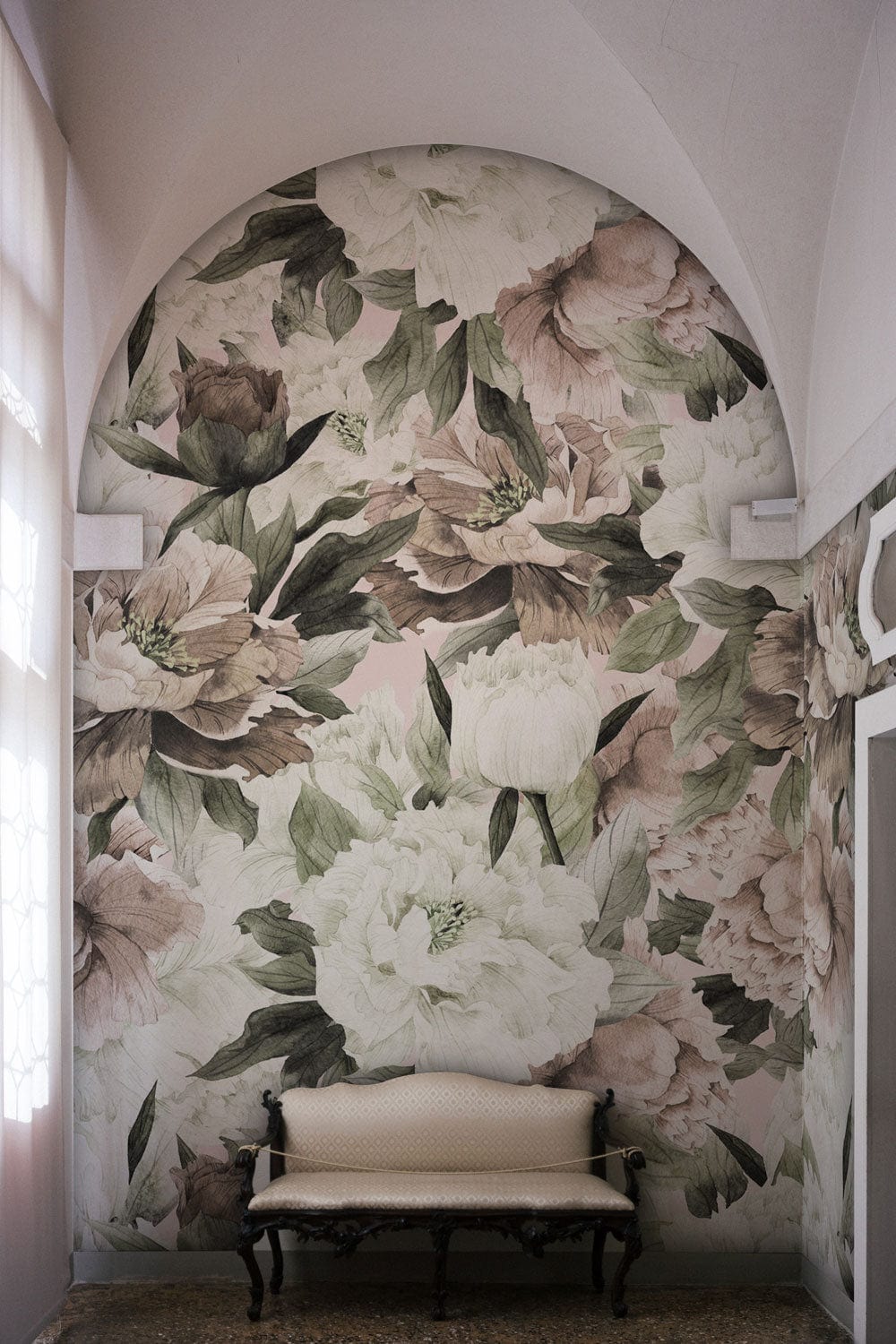 Alt text: Vintage Floral Blossom Mural in pastel; arched wall; elegant room; beige sofa; stone flooring.