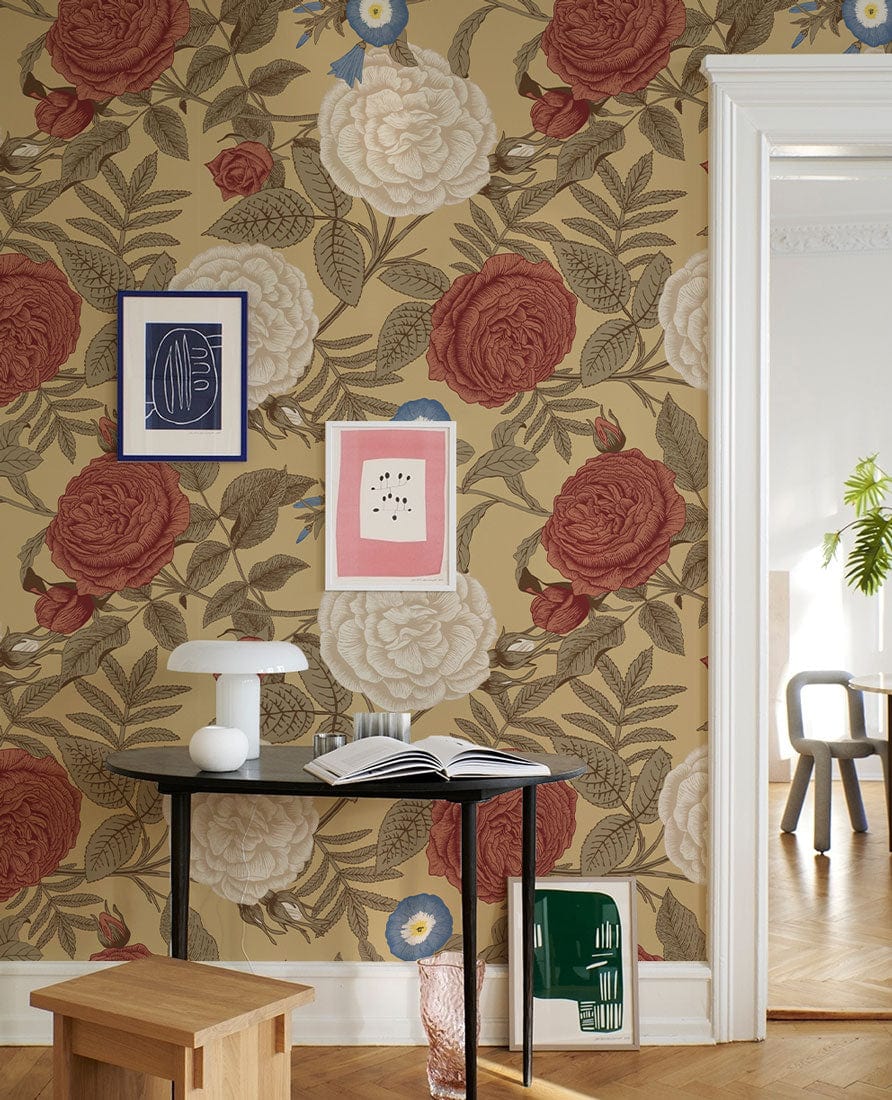Victorian floral wallpaper in red and white, wooden floor, minimalist bench, modern black table, framed art.