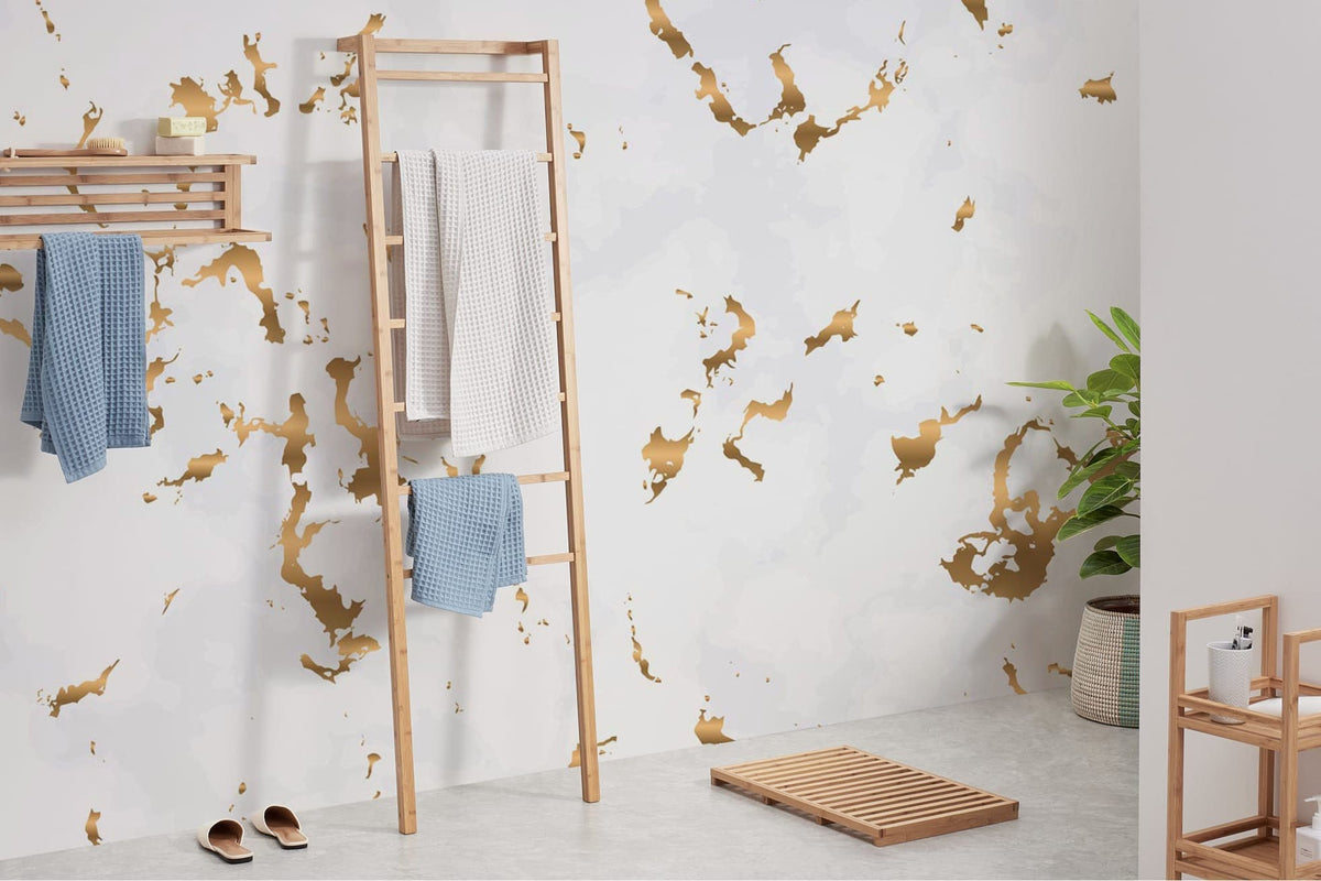Luxury gold and white marble effect wall mural in bathroom with wooden ladder and spa decor.