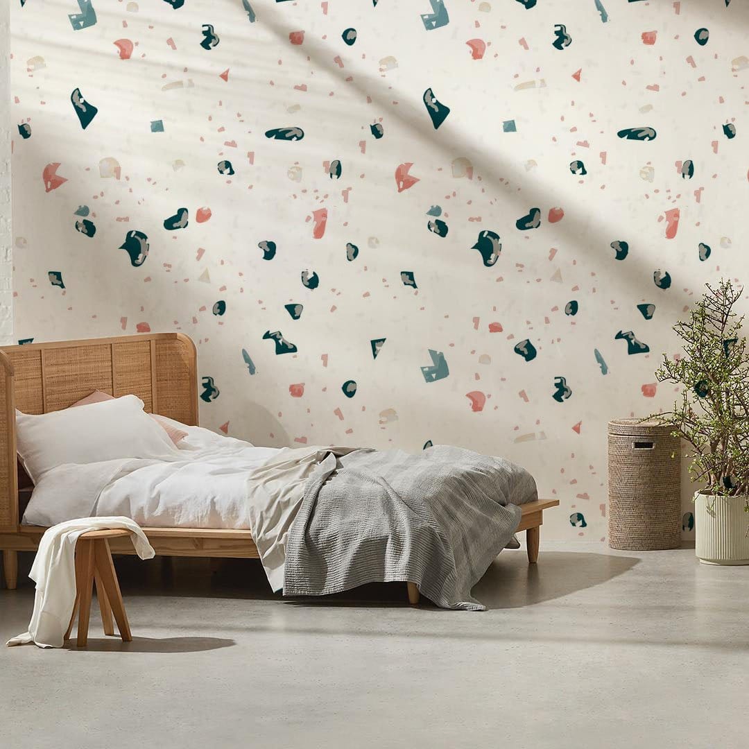 Contemporary terrazzo pattern wallpaper with pink and teal accents in bedroom, wooden bed, grey bedding.