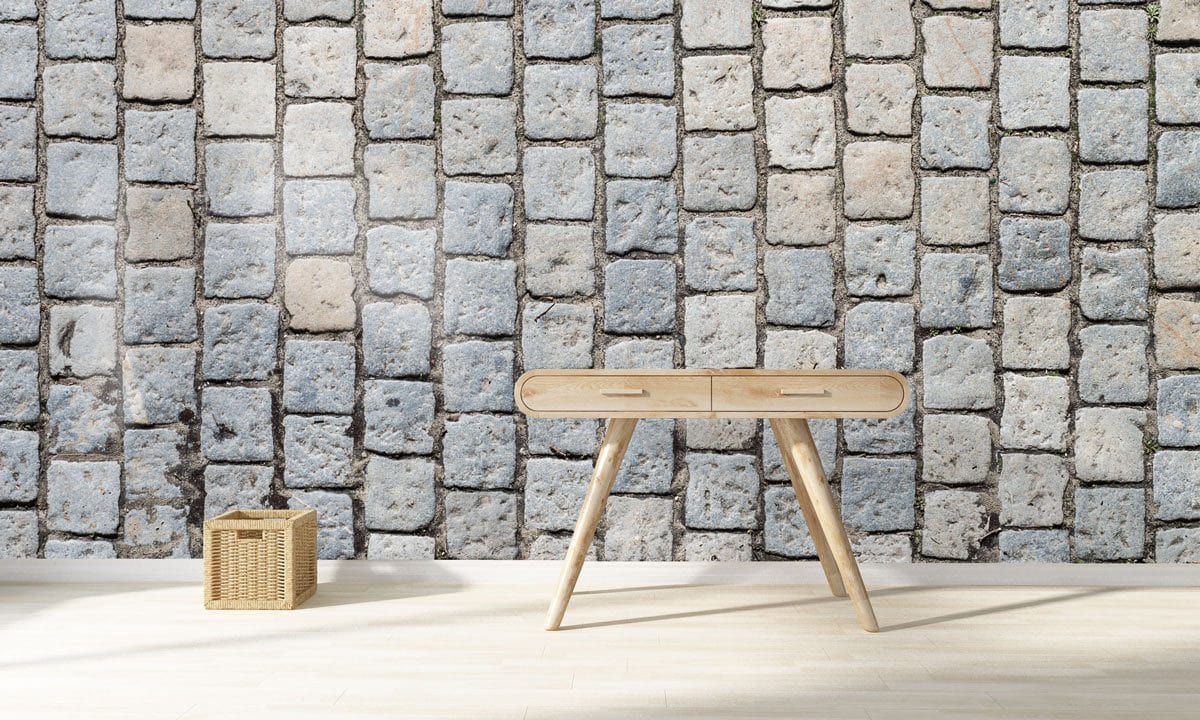 Vintage cobblestone pattern wallpaper in rustic grey beige, featuring light wooden desk on hardwood flooring.