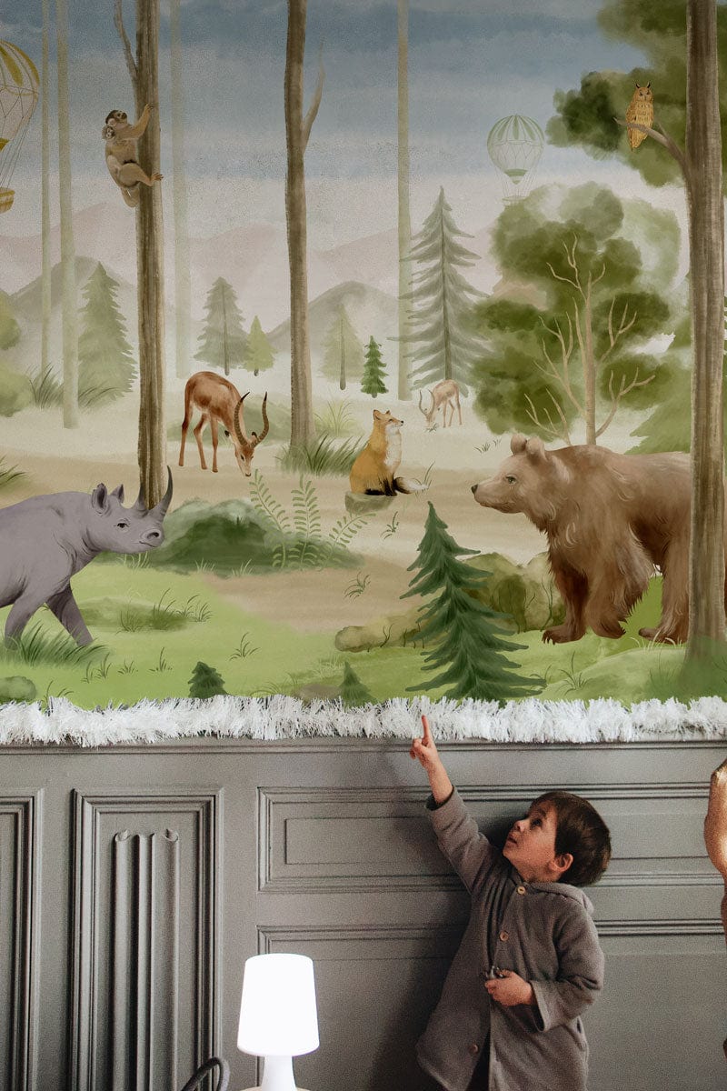 Child pointing at Scenic Forest Adventure Animal Mural, grey moulded wall panelling, children's room decor.
