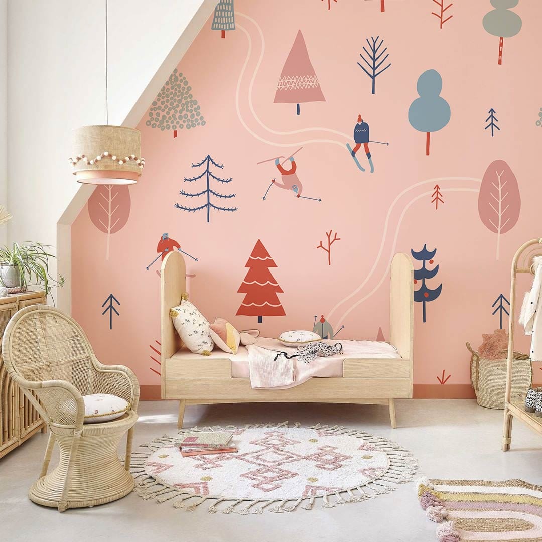 Winter Wonderland Skiers wallpaper in pastel pink; nursery with wicker furniture; cosy, vintage decor.
