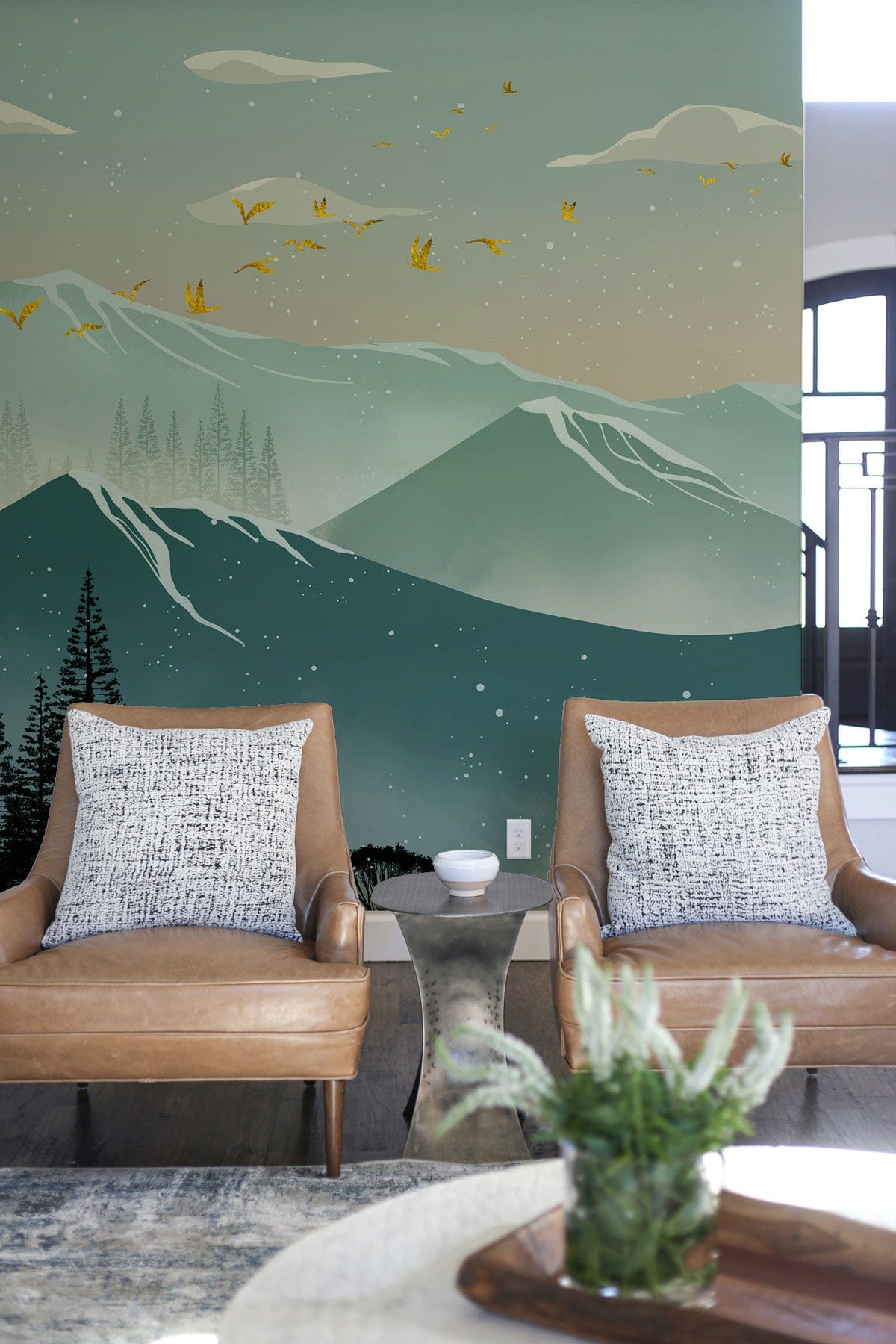 Teal mountain mural wallpaper in living room with tan armchairs and wooden flooring, serene decor style.