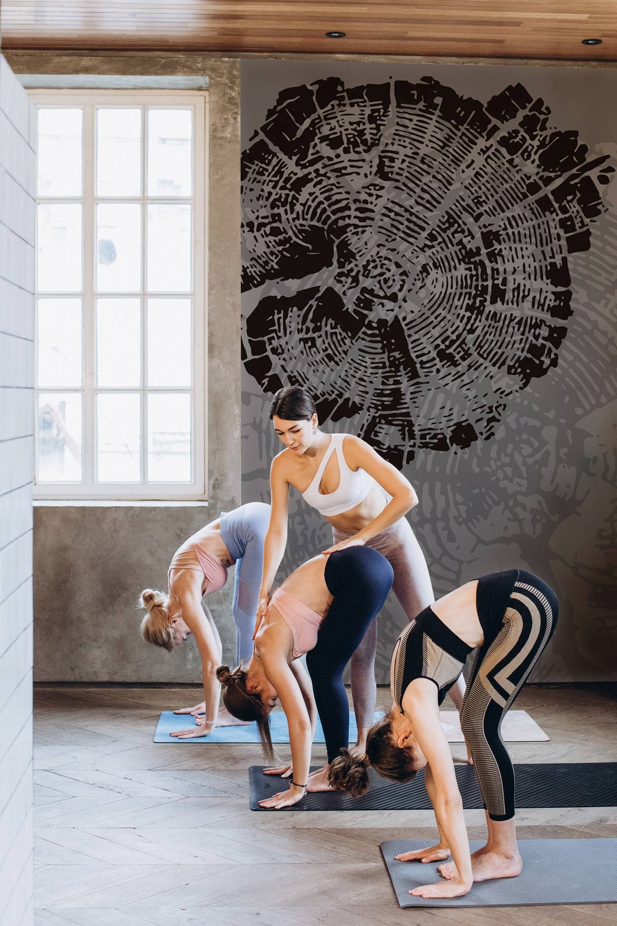 Yoga studio with grey and black tree rings mural wallpaper, wooden flooring, modern nature-inspired decor.