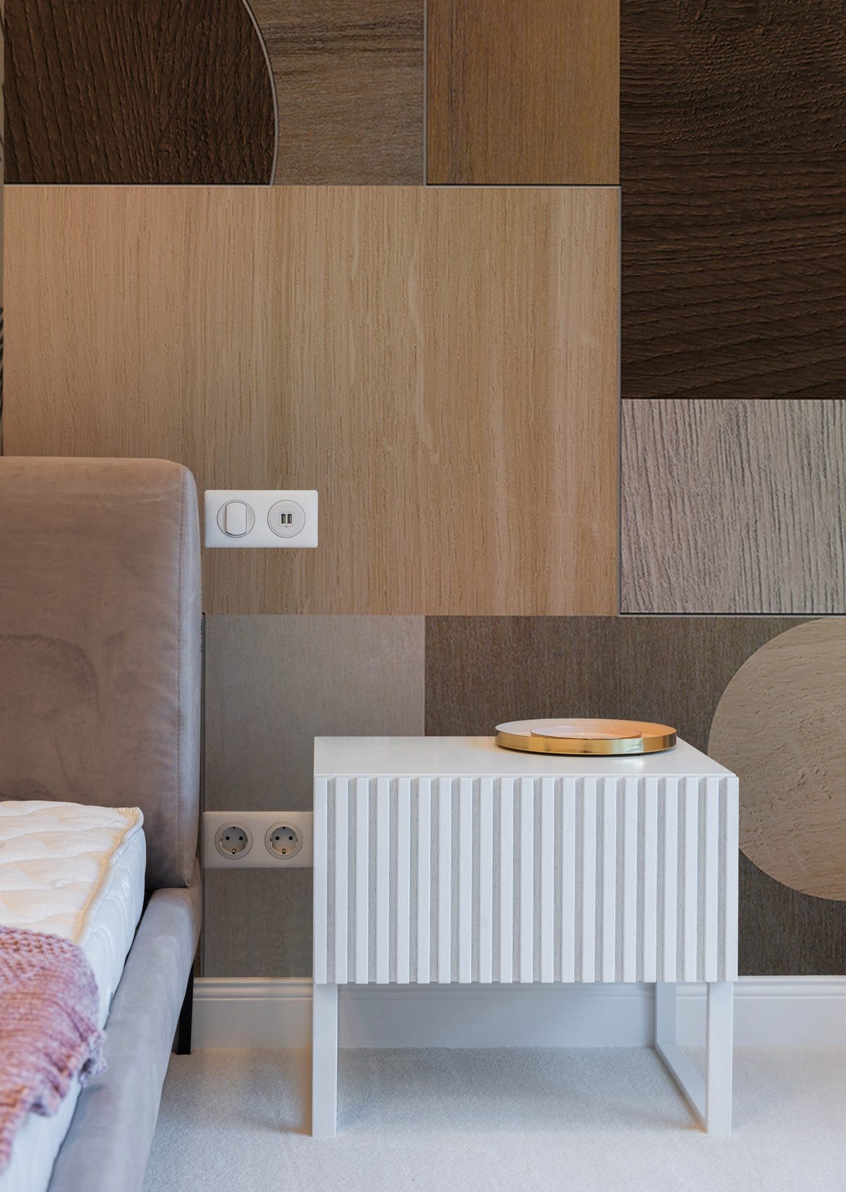 Geometric neutral tones wallpaper, modern style, beside taupe sofa, white bedside table in bedroom.