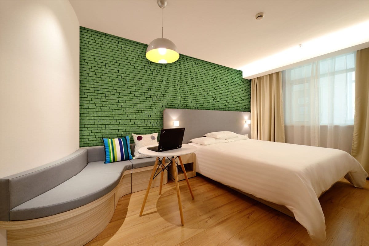 Green brick wallpaper in modern bedroom, grey sofa, wooden flooring, elegant interior, stylish design.