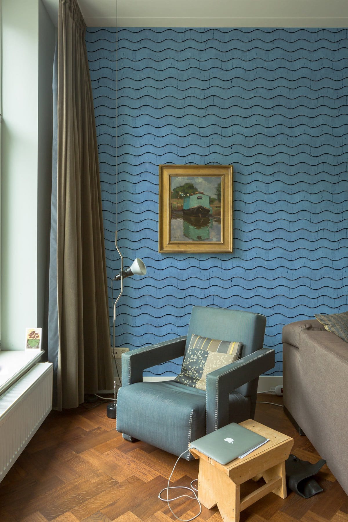 Tranquil Ocean Waves Blue wallpaper in cosy living room with grey armchair, parquet flooring, framed artwork.