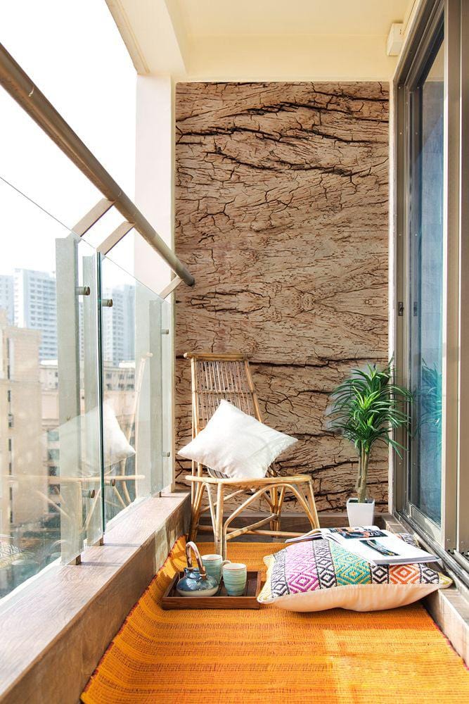 Natural Rustic Wood Texture Wallpaper on balcony with wicker chair, orange rug, and glass railing.