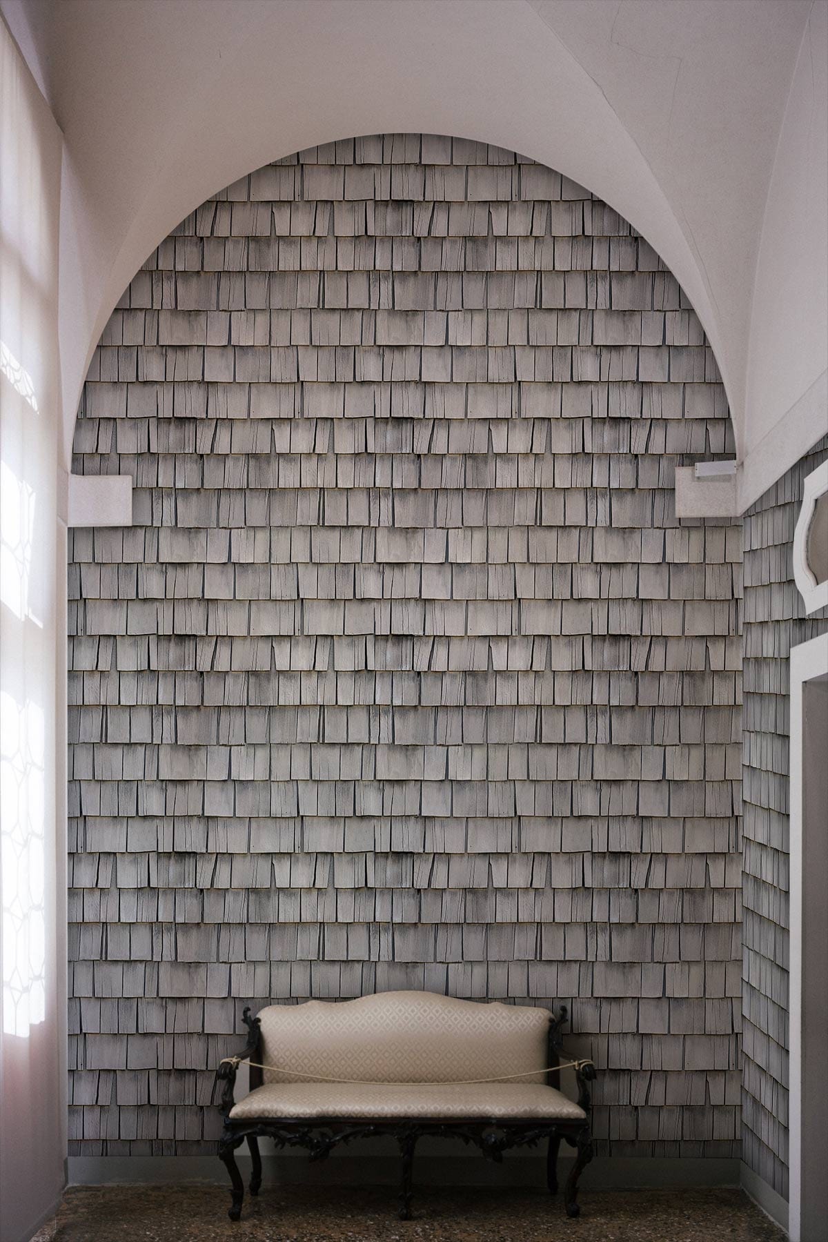 Elegant grey rippled wallpaper complements vintage white sofa; arched hallway with patterned design.