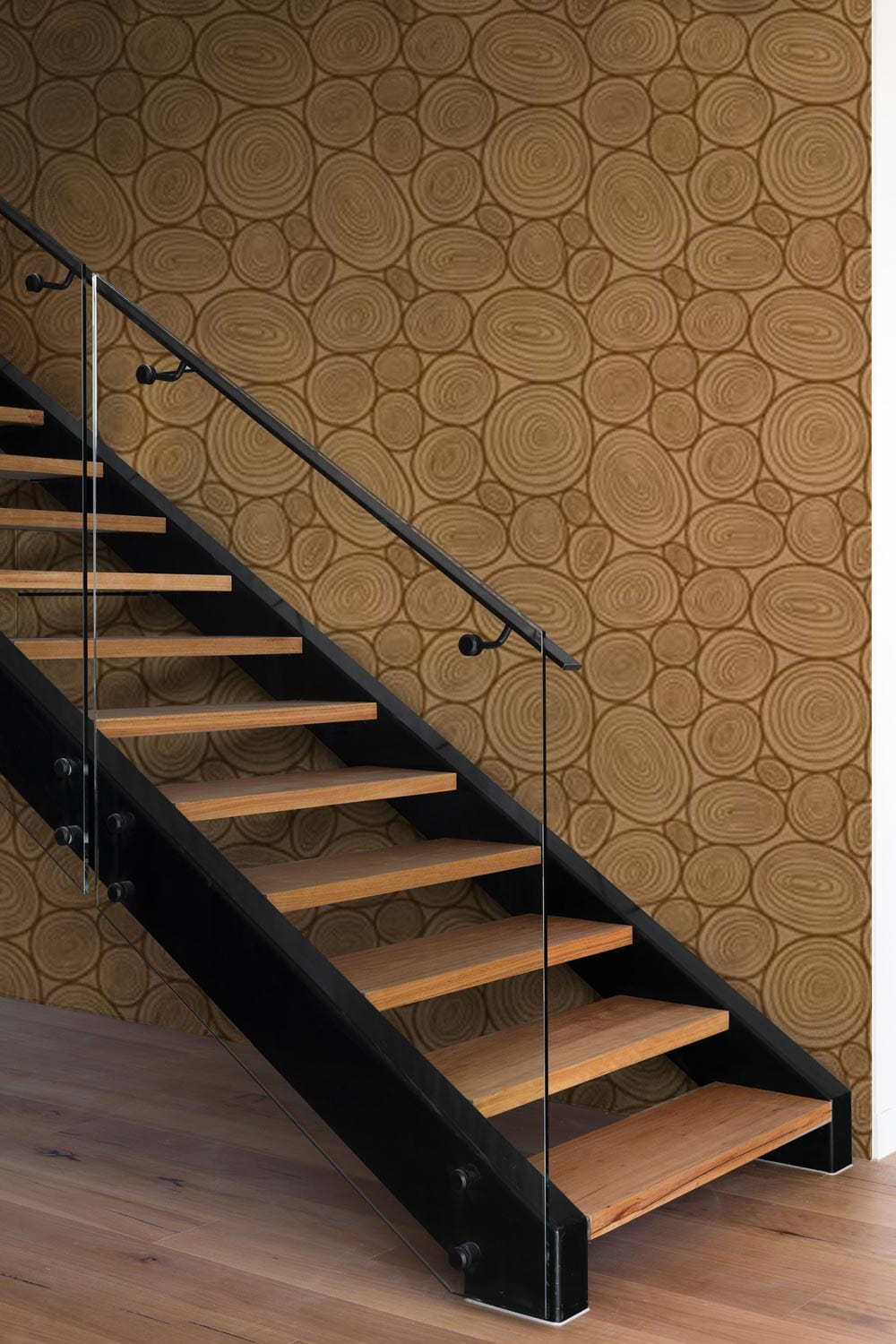 Geometric bronze oval pattern wallpaper in modern hallway with wooden staircase and glass railing.