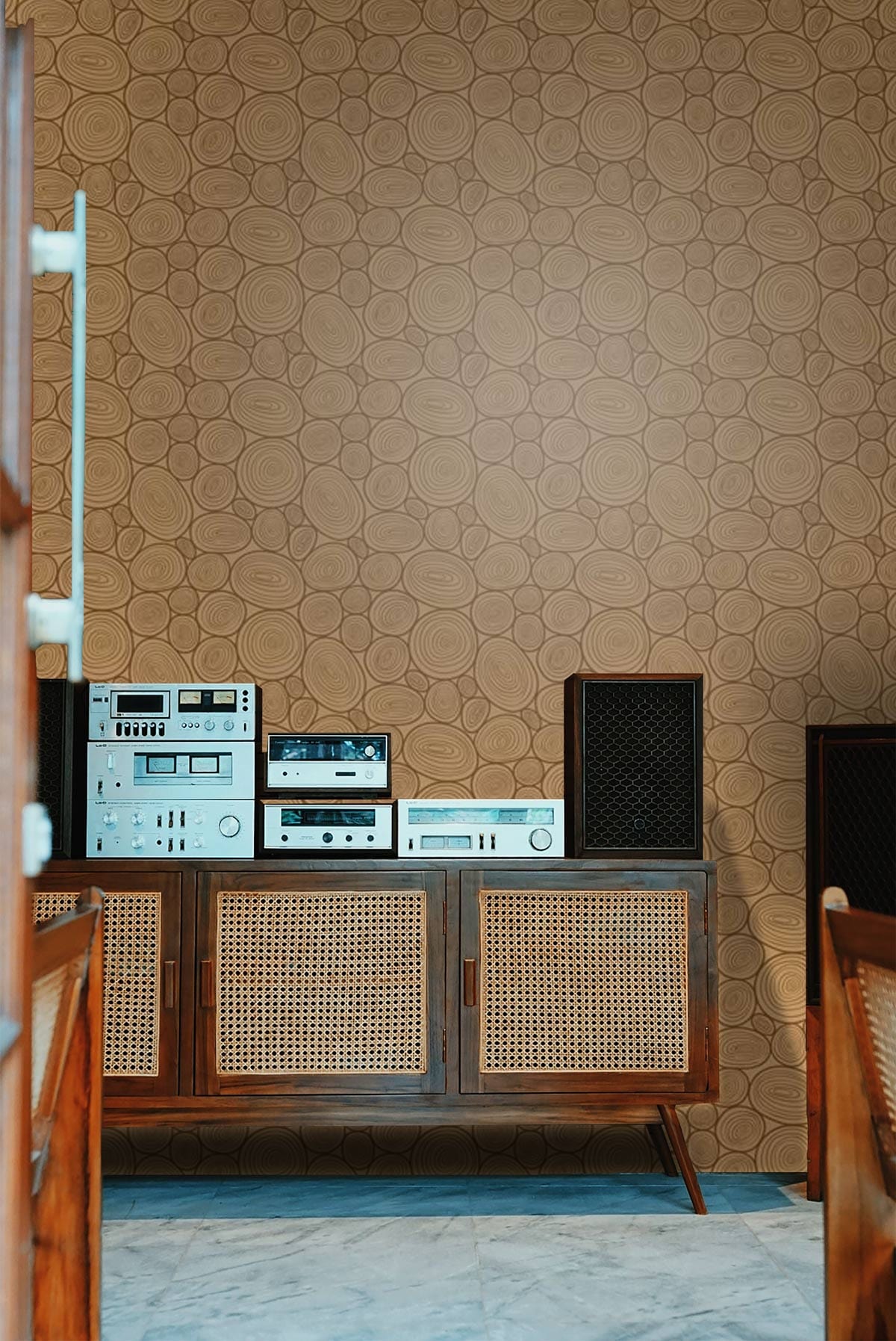 Geometric Bronze Oval Pattern Wallpaper in modern living room with retro wooden sideboard and stereo equipment.