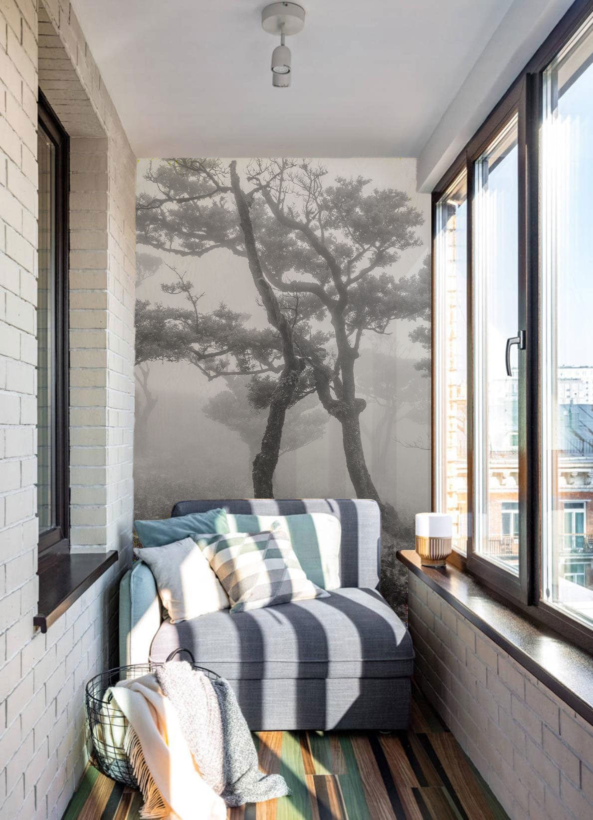 Monochrome misty forest mural in bright sunroom with grey sofa, striped flooring, brick walls.