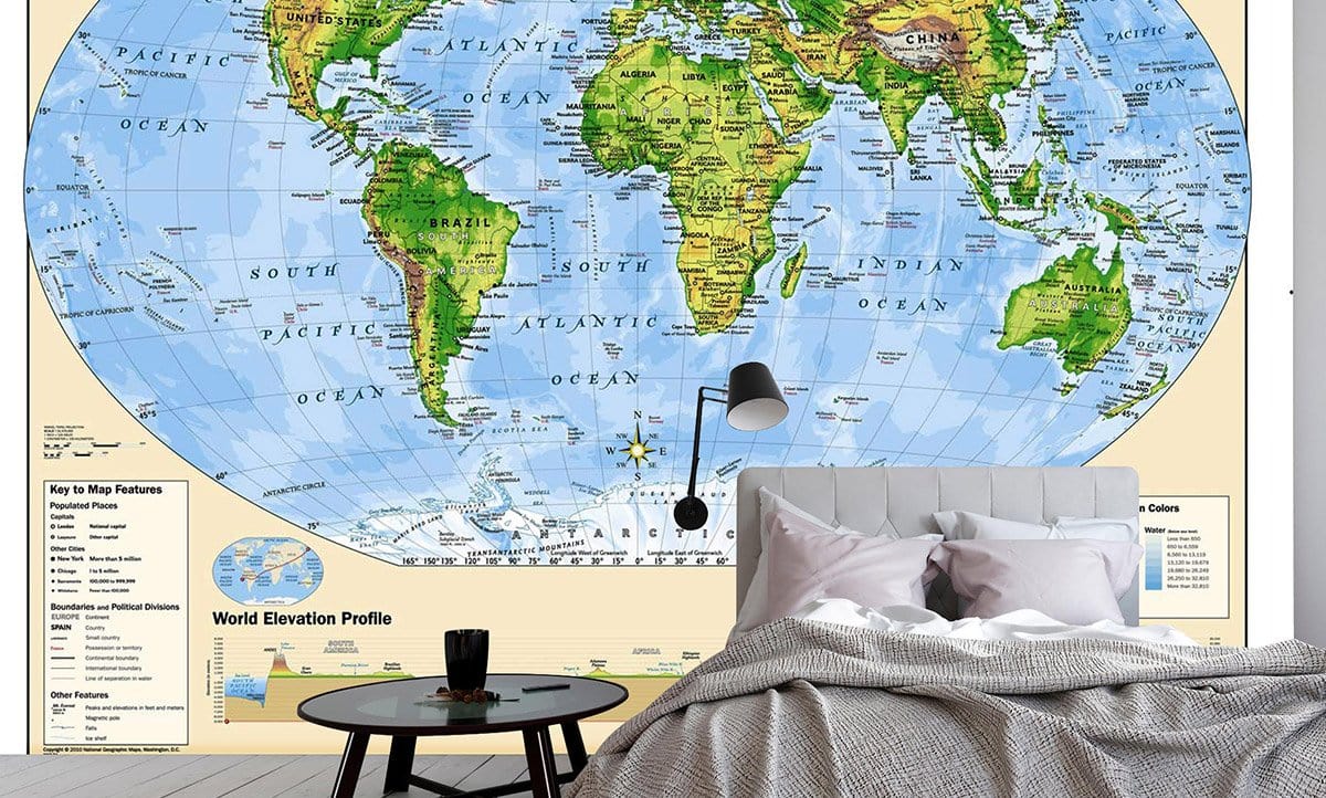 Vintage World Map Mural Wallpaper in green, blue adventure theme, grey bedding, wooden flooring.