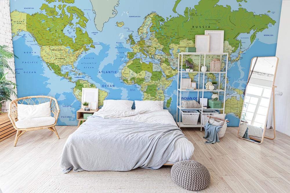 Vintage world map mural wallpaper in green and blue tones, bedroom setting, light wood flooring.