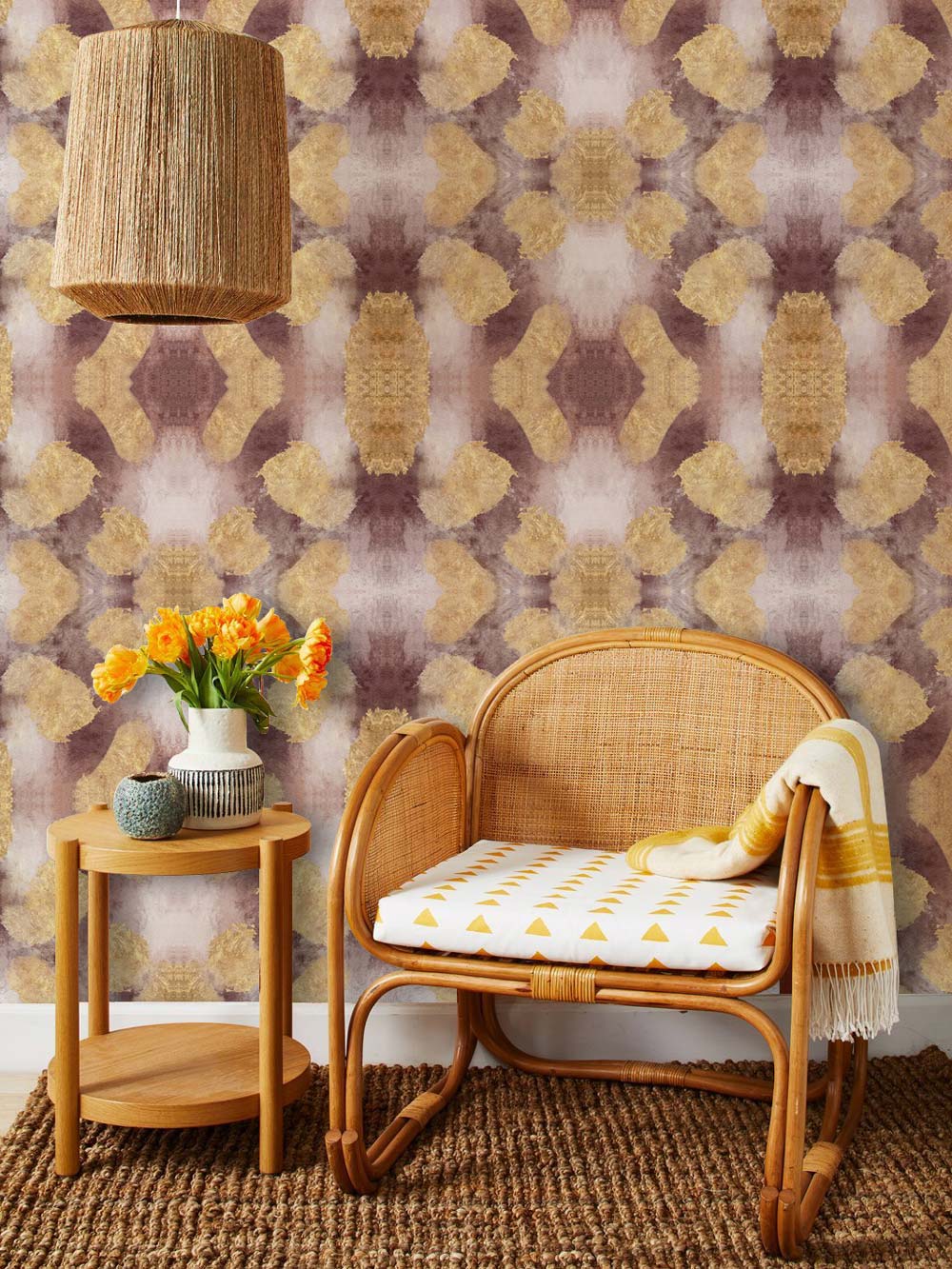 Vintage geometric wallpaper with wicker chair and wooden side table in cosy living room setting.