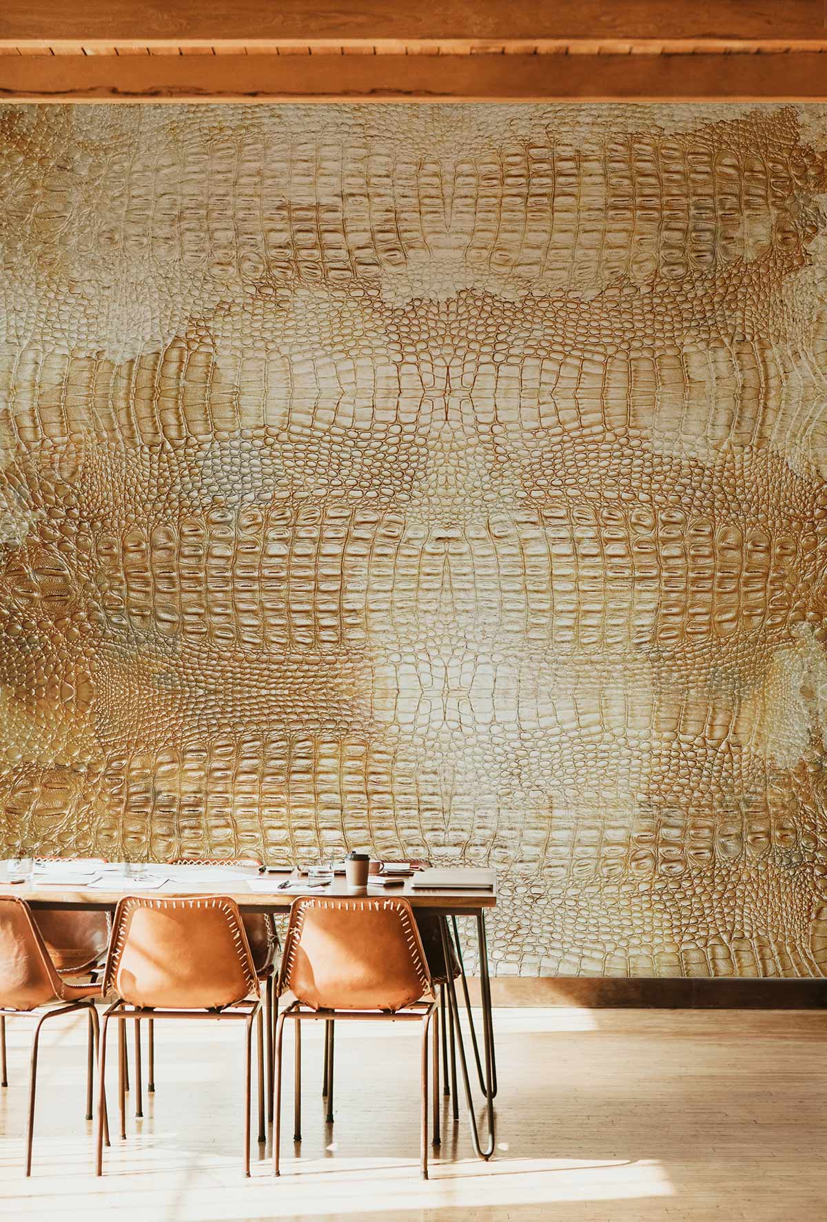 Textured beige faux leather crocodile wallpaper with brown dining chairs, wooden flooring, modern dining room setting.