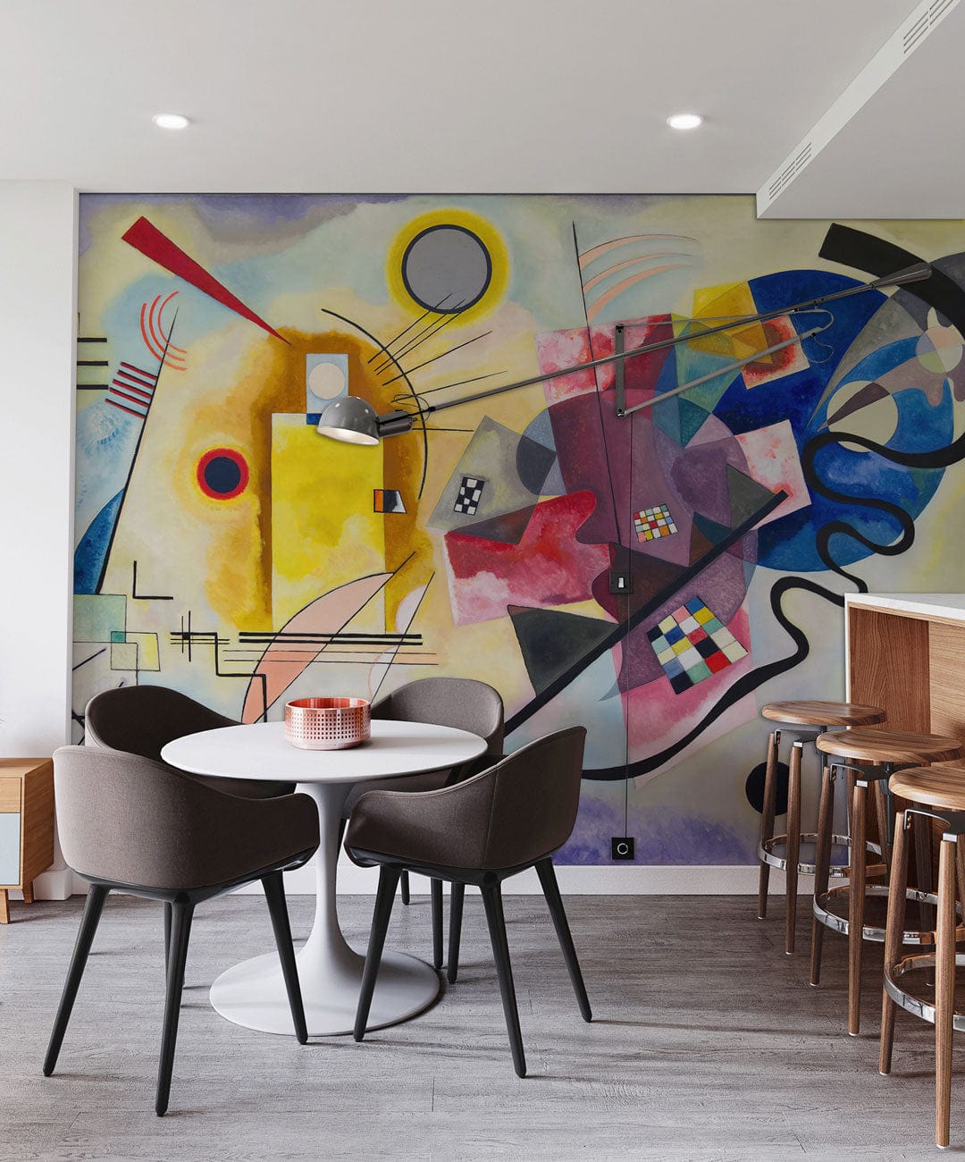 Vibrant abstract geometric mural wallpaper design in modern dining area, featuring grey chairs and wooden stools.