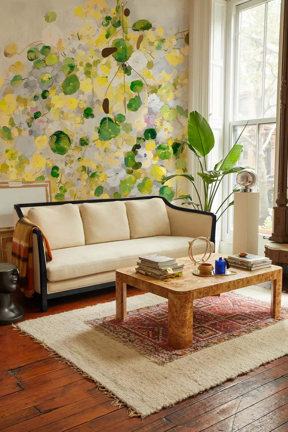Bright abstract floral watercolour mural wallpaper in cosy lounge with wooden flooring and cream sofa.