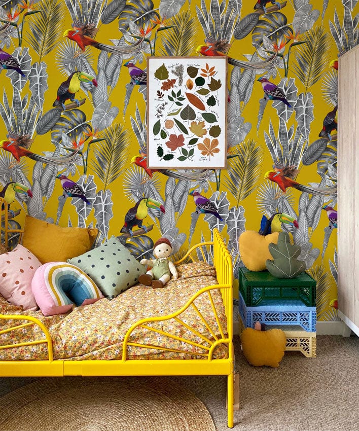 Mustard yellow botanical wallpaper, toucans, child's room, yellow bed, rug, decorative pillows, natural flooring.